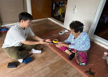 인제군청 담당자가 어르신에게 스마트기기를 설명하고 있다.  사진|인제군청