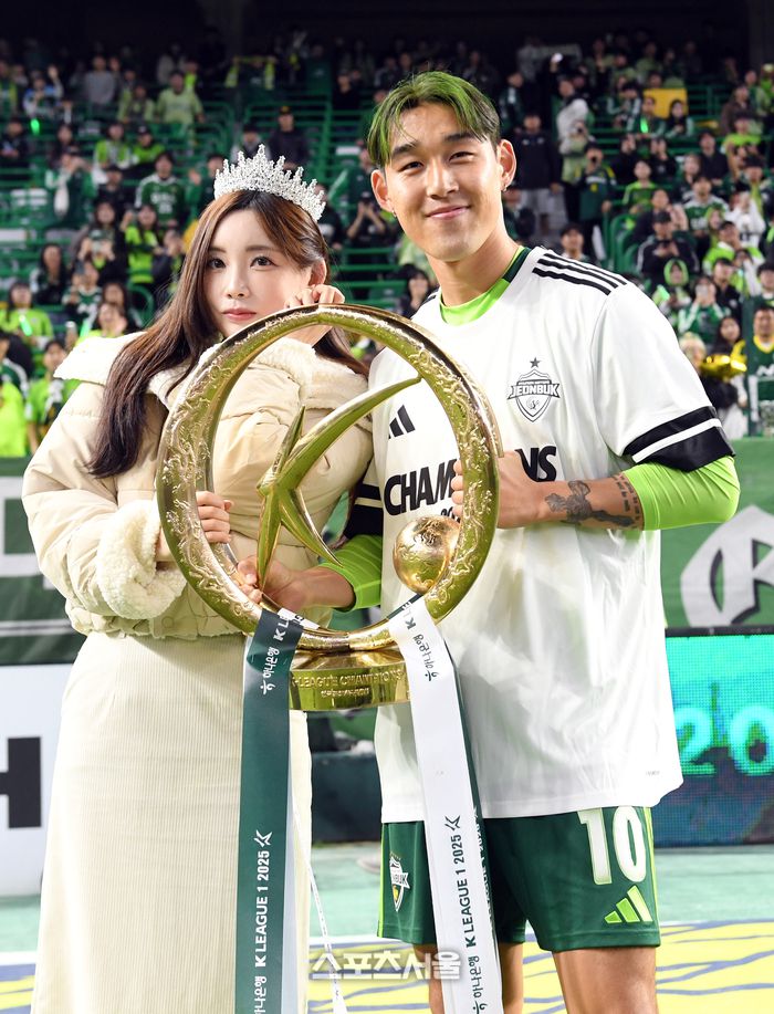 전북 현대의 송민규(오른쪽)가 8일 전주월드컵경기장에서 열린 하나은행 K리그1 대전 하나 시티즌과 경기 후 진행된 우승 기념 행사에서 팬들 앞에서  결혼을 앞둔 곽민선 아나운서에게 트로피를 건넨 뒤 기념촬영을 하고 있다. 2025. 11. 8. 전주 | 박진업 기자 upandup@sportsseoul.com
